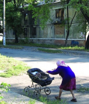 Жительница города Украинск на Донбассе везет полотняные мешки в старой детской коляске по центральной улице Первомайской. В домах выбиты окна. Балконы разобрали на металлолом
