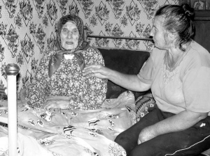 Наталя Кучерук (ліворуч) з села Кудіївці Жмеринського району на Вінниччині сидить на ліжку з донькою Надією. Вона поїла матір солодким чаєм, коли та спала