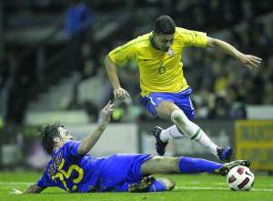 Левый защитник сборной Бразилии Андре Сантос (№ 6) проходит форварда украинский Артема Милевского