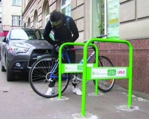 Андрій Чорнопищук пристібає велосипед до велопарковки по вулиці Лазарєва