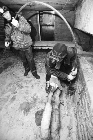 Працівники полтавської бригади ”Спрут” за допомогою гумового шланга підключають до каналізаційної мережі стояк львів’янки Любові Білій