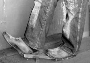 Денис Ямпольський з міста Гадяч на Полтавщині знімає черевики за допомогою збитих дощечок. Пристрій називається ”мальчик”