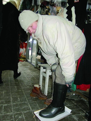 Продавець вінницького ринку ”Урожай” Тамара Шмендрак міряє валянки з калошами. Каже, відколи почались морози, їй холодно стояти в чоботах