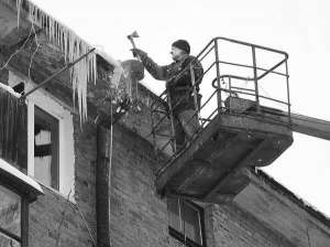 Покрівельник ЖЕКу №18 Петро Тума збиває бурульки з даху чотириповерхового будинку на вулиці Карла Маркса у Вінниці. За день встигає об’їхати 20 домів