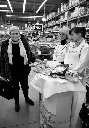 Покупців гіпермаркету ”Метро” на столичному Московському проспекті  пригощають стравами із напівфабрикатів і запрошують купувати продукцію ”Дригало”. Людмила Дригало (ліворуч) питає у дівчат-промоутерів про відгуки покупців