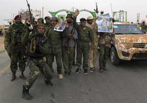Солдаты, верные своему лидеру Муамара Каддафи, празднуют победу над повстанцами возле города Аджабия в среду, 16 марта