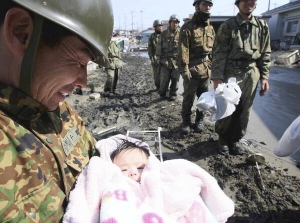 Японський рятувальник усміхається до чотиримісячної дівчинки, яку тримає на руках. Дитину витягли з-під завалів у місті Ішиномакі