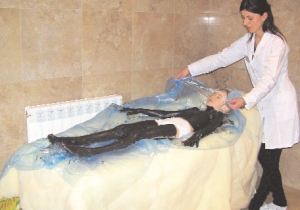 На одному із курортів Закарпаття медсестра Ірина Гутник обмастила грязями киянку 8-річну Софію Никончук. Закутує її ковдрою. У дівчини болять суглоби ніг. Так лежатиме 20 хвилин