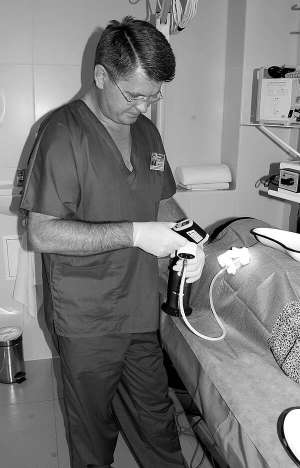 Донецький дерматолог Ігор Куценко обробляє рубець на тілі пацієнта рідким азотом. У правій руці тримає прилад, який показує температуру речовини