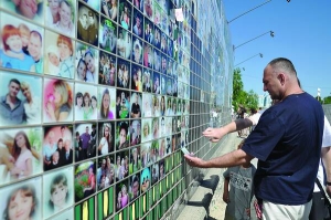 Черкасці роздивляються фото на стіні-мозаїці ”Ми — черкасці” у Долині троянд в обласному центрі. Її обіцяли заклеїти фотокартками до 10 червня. 28 червня на стіні ще є порожні клітинки