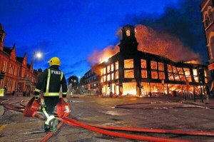 Пожежник проходить біля спаленого будинку в Тоттенхемі, північний Лондон, Велика Британія. Натовп напав на поліцейських і спалив дві патрульні машини після того, як минулого тижня офіцер поліції застрелив чорношкірого Марка Даґґана