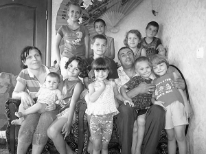 Світлана і Євгеній Ісаєви з дітьми у вітальні свого будинку в селі Червоне на Донеччині. Сімох вони всиновили та взяли під опіку. Двох народили самі. Ще один, Юрій, прийшов до них у гості. Ним опікується Геннадій Мохненко, директор Маріупольського притулку для сиріт ”Пілігрим”