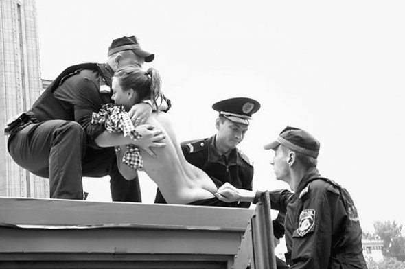 Міліціонери стягують із автозака активістку з жіночого руху ”Фемен” 16 серпня у Києві. Вона протестувала проти утримання під вартою екс-прем’єра Юлії Тимошенко