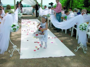 Дівчинка стелить доріжку із пелюсток троянд під час виїзної весільної церемонії в парку 50-річчя в Черкасах