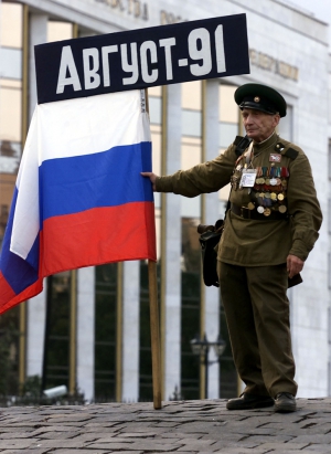 Мужчина держит российский флаг под зданием правительства в Москве 19 августа 2011