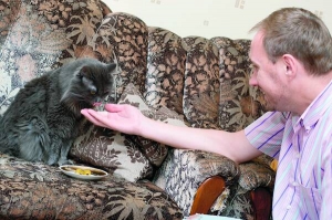 Полтавський дизайнер Юрій Матвєєв годує свого кота Гаса оливками