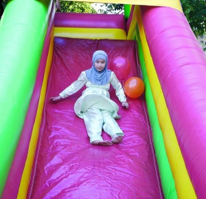 Мусульманська дівчинка у хіджабі спускається з надувної гірки біля столичного ісламського центру. Там у вівторок, 30 серпня, відсвяткували закінчення посту Рамадан
