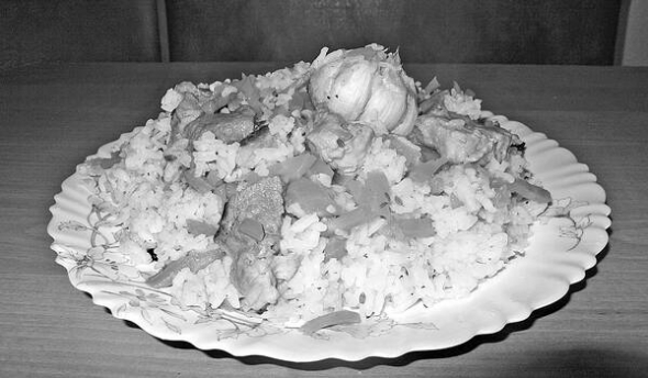 Плов выкладывают на большое блюдо слоями - рис, морковь, мясо. Украшают головками чеснока