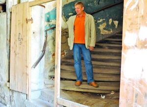 Заступник директора львівського театру імені Марії Заньковецької Роман Порада стоїть при вході у під’їзд із житловими приміщеннями. За його спиною видно облущені стіни, продавлені сходи