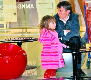 Киянин забавляє доньку і чекає на свою дружину біля магазину іспанського бренду ”Зара” у столичному торговельному центрі ”Караван”, де триває ніч розпродажу