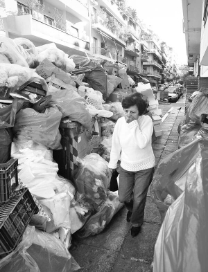 Жінка прикриває ніс, проходячи повз купи сміття під час страйку комунальних служб та сміттєзбиральників у грецькій столиці Афіни у середу, 19 жовтня. Вчора почався найбільший за останні роки у країні масовий дводобовий страйк. Цього тижня парламент Греції має проголосувати за план жорсткої економії, щоб отримати кредит Євросоюзу та Міжнародного валютного фонду для виходу з кризи