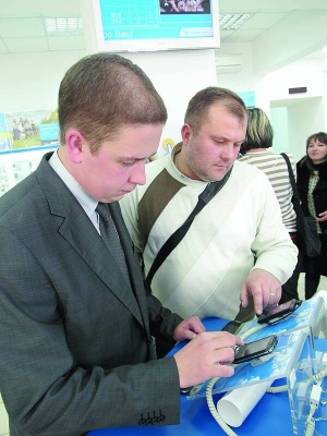 Володимир Дзюбанов (ліворуч) із компанії ”Київстар” показує фірмові смартфони відвідувачеві центру обслуговування абонентів у Харкові