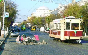 Працівники дорожньої служби на дорозі біля Вінницького міськвиконкому роздивляються ретро-трамвай. Усередині оркестр трамвайно-тролейбусного управління грає веселу музику