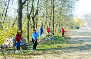 Жителі села Бунів Яворівського району в понеділок зранку згрібають листя на центральній дорозі біля церкви. Готуються до храмового свята