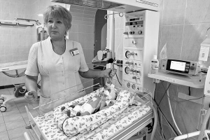 Заввідділу реанімації та терапії столичного п’ятого пологового будинку Тетяна Риловнікова стоїть поряд із новонародженим немовлям. Хлопець народився недоношеним, через те його легені штучно вентилюють