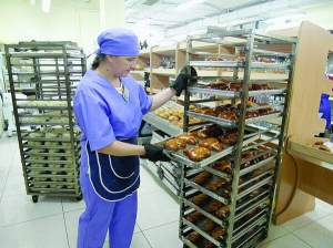 Пекар полтавського супермаркету ”Ко-ко” Наталія Шпак дістає щойно спечені булки. Гарячу випічку швидко розбирають