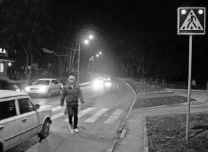 Чоловік іде вулицею Отокара Яроша в Харкові. Ліхтарі, вмонтовані в дорогу вздовж пішохідного переходу, світяться, доки не ступить на тротуар