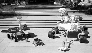 Моделі марсоходів у натуральну величину на виставці перед фасадом Лабораторії реактивного руху неподалік Лос-Анджелеса, що в американському штаті Каліфорнія. Два марсоходи типу ”Марс Експлорейшн Ровер” (ліворуч) досліджують червону планету зараз. У 1996-1997 роках там працював ”Соджорнер” (у центрі), з наступного року естафету підхопить ”Кюріосіті” (праворуч)