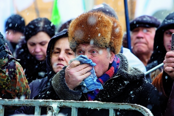 Учасник мітингу на Софійській площі в Києві з нагоди Дня соборності та свободи України витирає обличчя хусткою. 22 січня столицю засипало мокрим снігом