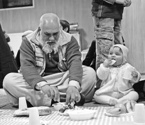 Чоловік привів дитину на святкування дня народження пророка Мухаммада у київську мечеть Ар-Рахма. Сидячи на килимках, вони їдять плов та фрукти