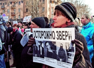 Учасниця мітингу з вимогою справедливого суду над ґвалтівниками Оксани Макар тримає плакат з їхніми портретами. Мітинг відбувся в Миколаєві 15 березня