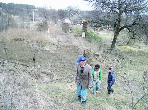 Анатолій Гладін з онуками ходить біля руїн хати за селом Пологи Пологівського району Запорізької області. Її колись винаймав серійний убивця Сергій Ткач. Після його затримання селяни розграбували й повалили помешкання. Залишилася лише стіна з іконою