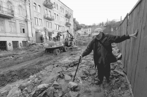 Чоловік іде столичним Андріївським узвозом. Вулиця залишається без бруківки. Роботи на місці зруйнованих трьох будинків припинили. Працівників направили на монтаж комунікацій та оновлення фасадів домів