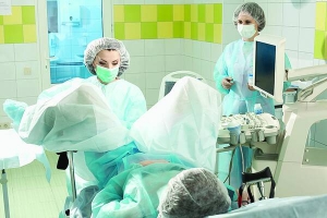Головний лікар столичної клініки Лілія Давид оглядає пацієнтку. Жінці видалили маткові труби, але після цього вона змогла завагітніти. Поряд стоїть медсестра 