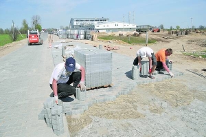Чоловіки кладуть бруківку на дорозі до села Басівка Пустомитівського району. Позаду видно будівлю ”Транссервіс”, яке замовило роботу