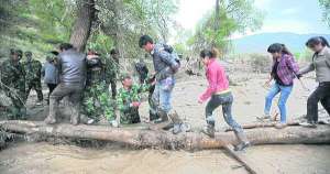 Солдати допомагають жителям села Гумень китайської провінції Ганьсу перейти по колоді через потік грязюки, після того як минулого четверга дощ із градом спричинив потужні зсуви. Сотні будинків були зруйновані, під завалами загинули щонайменше 53 людини, 18 зникли безвісти