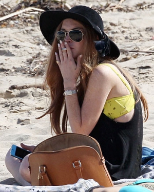 Скандально відома актриса Ліндсі Лохан нервово курить  на пляжі в Малібу.