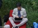29-летний Дмитрий Потехин сидит с ноутбуком на коленях среди травы на чем-то похожем на кресло без ножек