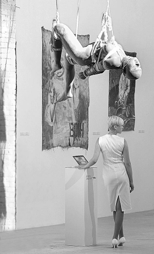 Відвідувачка розглядає полотна під час відкриття бієнале сучасного мистецтва ”Арсенале-2012” у столичному ”Мистецькому Арсеналі”. Під стелею висить скульптура чорношкірої жінки. Це проект ”Божество Маркс” шанхайської арт-групи ”МейдІн Компані”