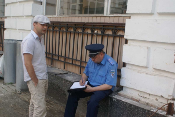 Людина у формі майора міліції відбирає пояснення в громадського активіста Дмитра Потєхіна