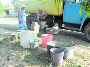 Жителі вулиці Механізаторів у Ладижині Тетяна Барвінок і Володимир Пріщенко набирають воду у старі бідони і відра