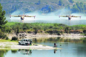 Літаки набирають воду із резервуара. Нею гасять лісові пожежі неподалік найбільшого заповідника Сьєрра де Маріола іспанської провінції Аліканте. 
Полум’я важко здолати через сильний вітер