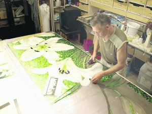 Столичний художник Сергій Попов викладає з мозаїки лілеї. Обтинає краї деталей, щоб щільніше лягли