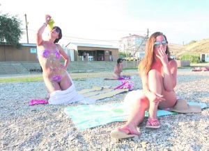 Дівчата засмагають на нудистському пляжі у кримському селищі Коктебель. Одній із них місцеві пляжні художники розмалювали тіло. У морській воді візерунки змиваються за два дні