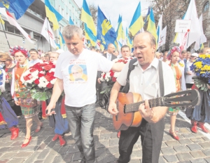 Нардеп-”бютівець” Юрій Одарченко з гітаристом іде попереду колони опозиції 24 серпня. За ними 12 хлопців та дівчат у національних костюмах, лідери восьми опозиційних партій