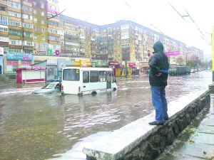 У місті Кіровоград 8 жовтня чоловік фотографує на мобільний телефон вулицю 50-ліття Жовтня, залиту дощовою водою. Через забиту каналізацію потік води сягав одного метра